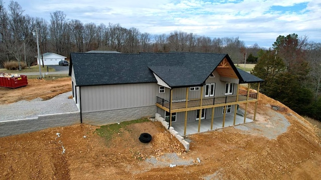 exterior space with a deck, dirt driveway, and a shingled roof