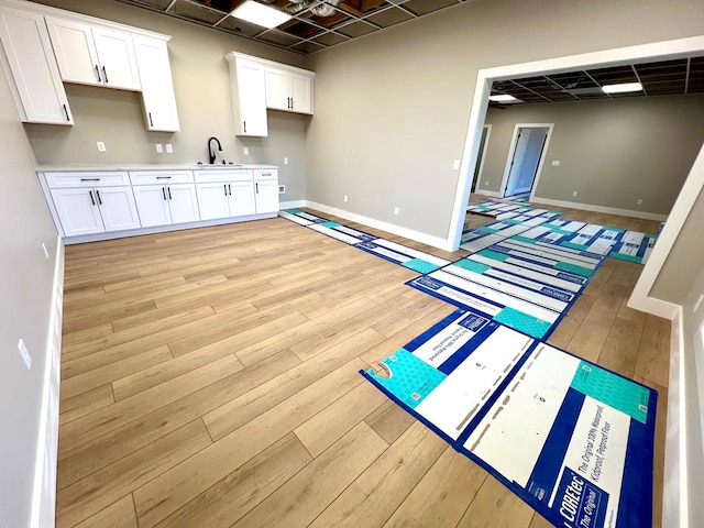 kitchen featuring light countertops, a sink, light wood-style flooring, and white cabinets