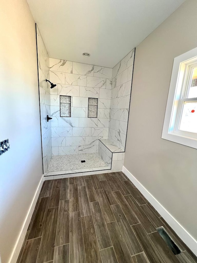 bathroom featuring wood tiled floor, baseboards, and a walk in shower