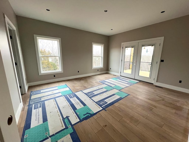 spare room with light wood-style flooring, baseboards, and french doors