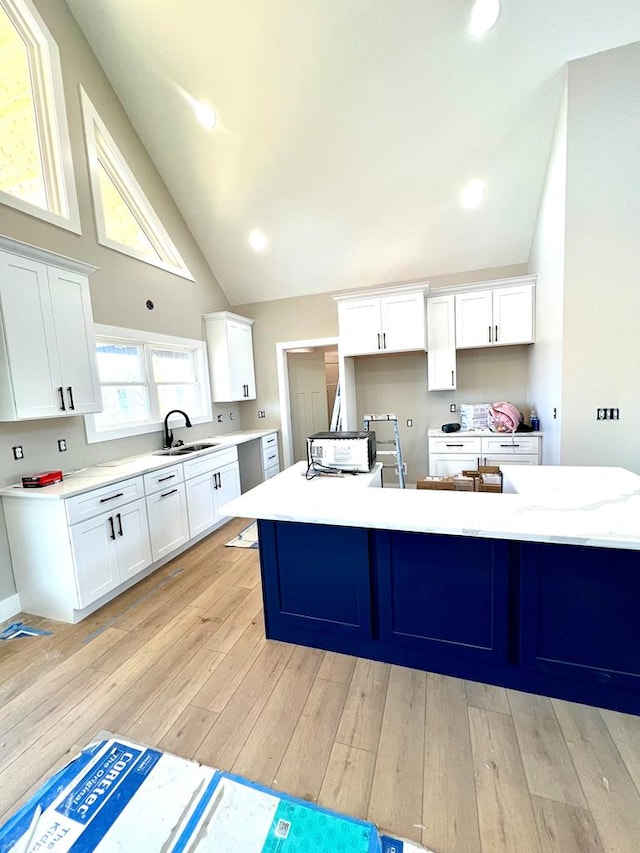 kitchen featuring white cabinets, a kitchen island with sink, light wood-style floors, a sink, and recessed lighting