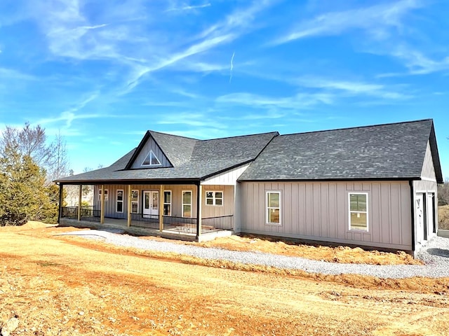 view of front facade with a shingled roof, covered porch, and board and batten siding