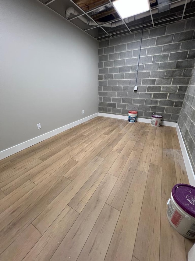 finished basement with concrete block wall, baseboards, and wood finished floors