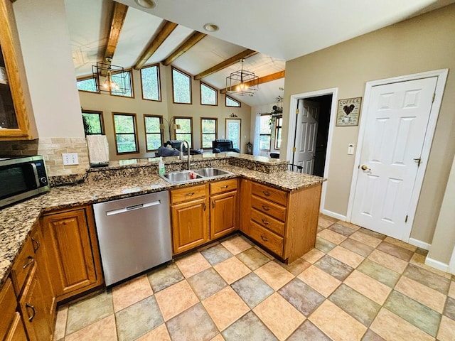 kitchen featuring stainless steel appliances, a peninsula, a sink, open floor plan, and brown cabinets