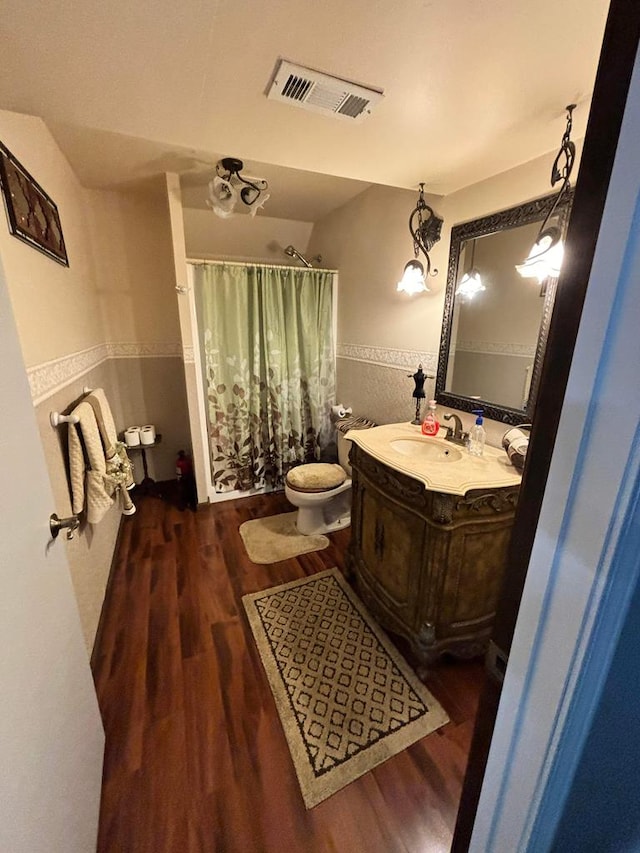 full bathroom with vanity, a shower with shower curtain, wood finished floors, and visible vents