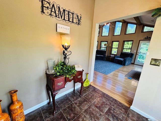 interior space with high vaulted ceiling, dark wood-type flooring, beam ceiling, and baseboards