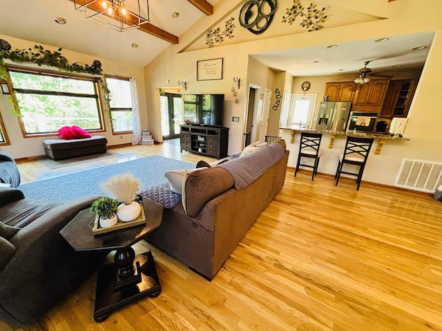 living room featuring light wood-type flooring, visible vents, and beam ceiling