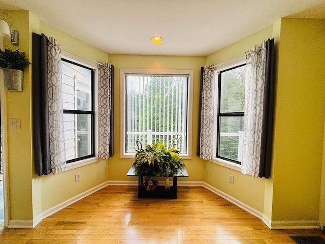 empty room with light wood-style floors, visible vents, and baseboards