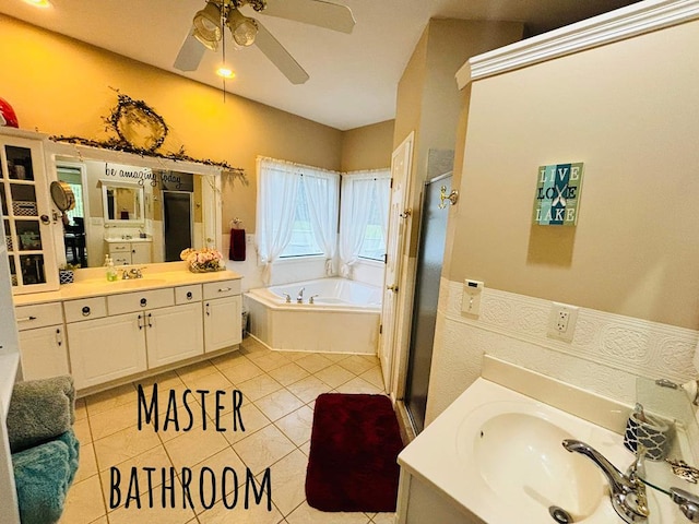 full bathroom featuring a stall shower, a bath, two vanities, tile patterned floors, and a sink