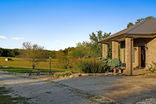 exterior space featuring driveway, metal roof, and brick siding