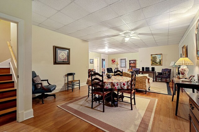 dining room featuring a paneled ceiling, stairway, ceiling fan, light wood-type flooring, and baseboards