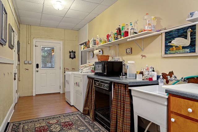 kitchen with black microwave, a drop ceiling, washer and dryer, brown cabinets, and open shelves