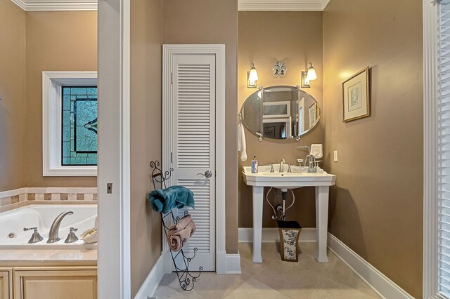 full bathroom featuring a tub to relax in, baseboards, ornamental molding, tile patterned flooring, and a sink