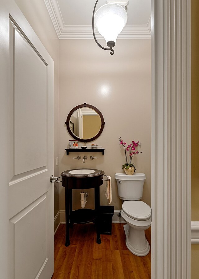 bathroom featuring ornamental molding, wood finished floors, toilet, and baseboards