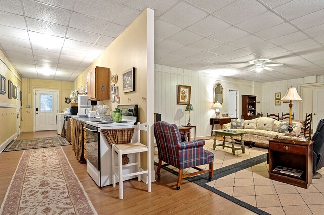 living room with light wood-type flooring, ceiling fan, and a drop ceiling