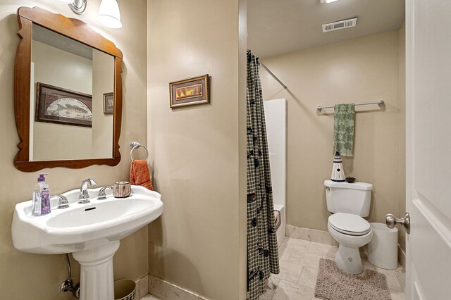 bathroom with shower / tub combo, baseboards, visible vents, and toilet