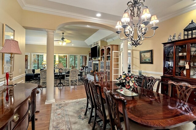 dining area with light wood-type flooring, ornate columns, arched walkways, and crown molding