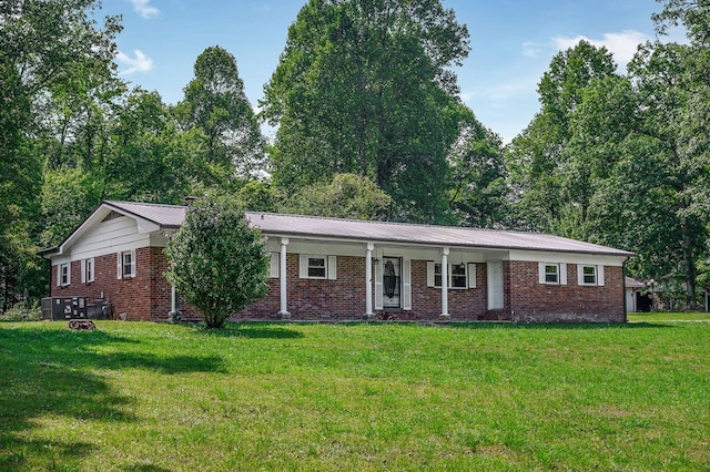 ranch-style home featuring metal roof, brick siding, a front yard, and cooling unit