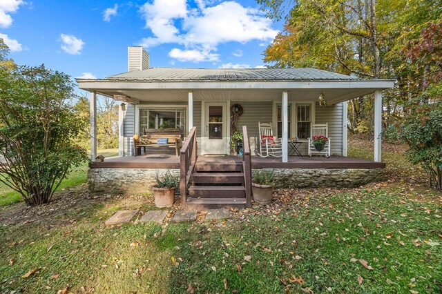 view of front of property with covered porch, metal roof, and a chimney