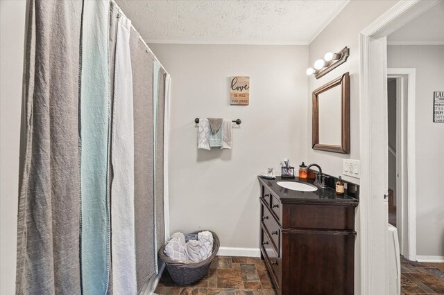 full bath with crown molding, stone tile flooring, vanity, a textured ceiling, and baseboards