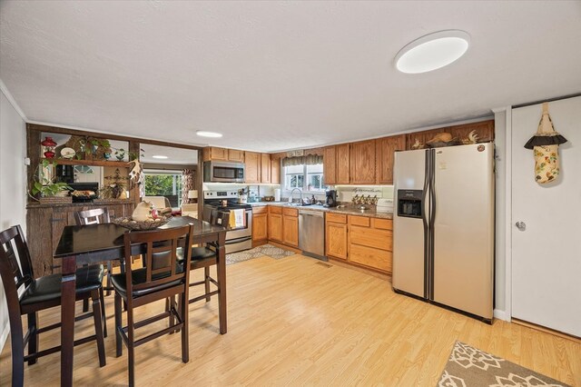 kitchen with dark countertops, light wood-style flooring, appliances with stainless steel finishes, and a sink