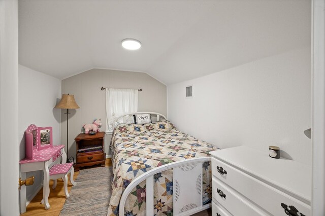 bedroom with lofted ceiling, wood finished floors, and visible vents