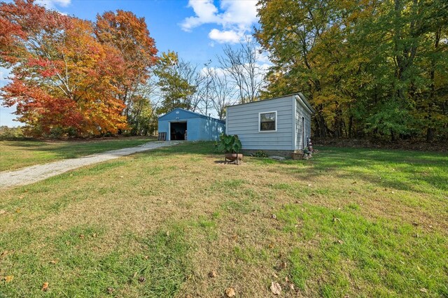 view of yard featuring driveway, a detached garage, and an outbuilding