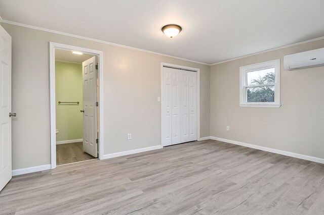 unfurnished bedroom featuring light wood-style floors, ornamental molding, baseboards, and a wall mounted AC