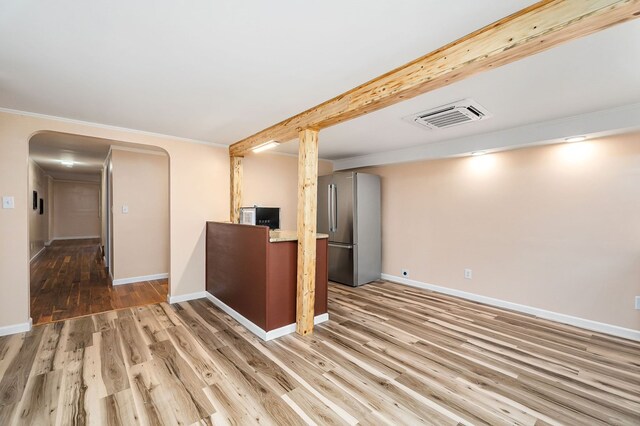 kitchen featuring arched walkways, wood finished floors, visible vents, baseboards, and freestanding refrigerator