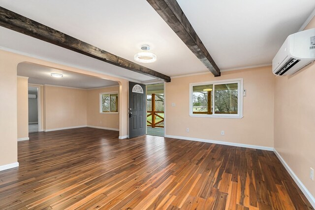 spare room featuring dark wood-style floors, beam ceiling, a wall mounted air conditioner, and baseboards