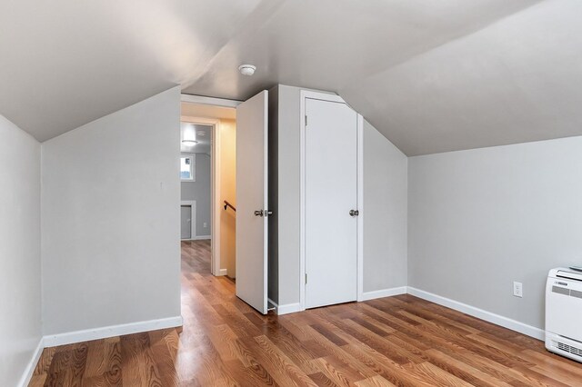 bonus room featuring lofted ceiling, heating unit, wood finished floors, and baseboards