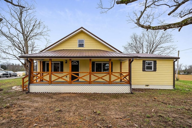 back of property with metal roof, a porch, and crawl space