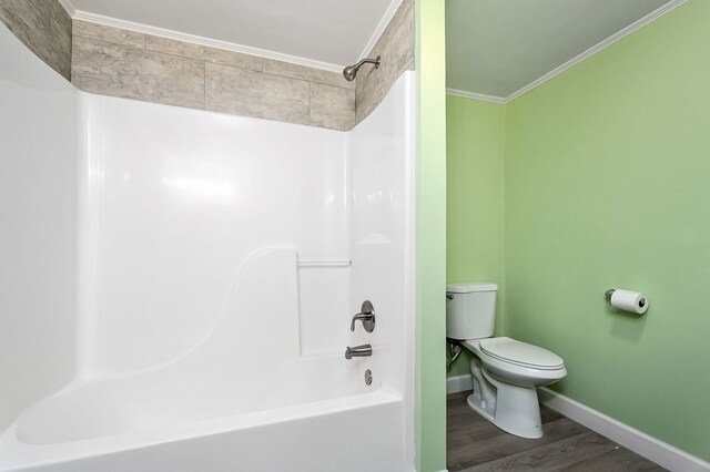 full bathroom with shower / bathtub combination, toilet, ornamental molding, wood finished floors, and baseboards