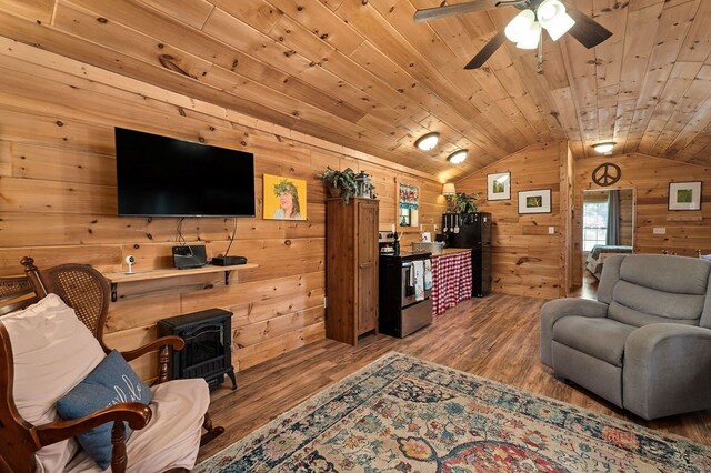 living area with wood ceiling, wood finished floors, a wood stove, and vaulted ceiling