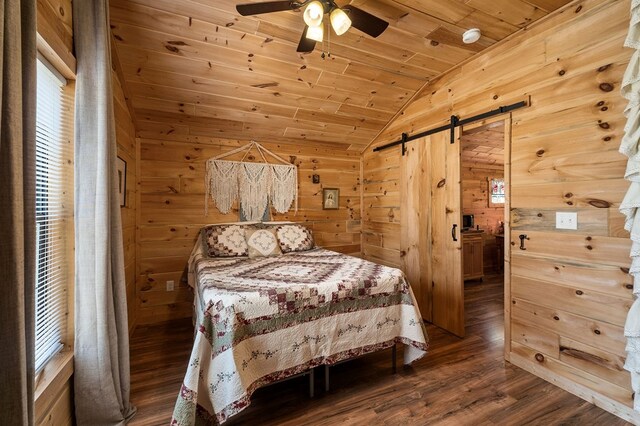 bedroom with wood walls, lofted ceiling, a barn door, wooden ceiling, and wood finished floors