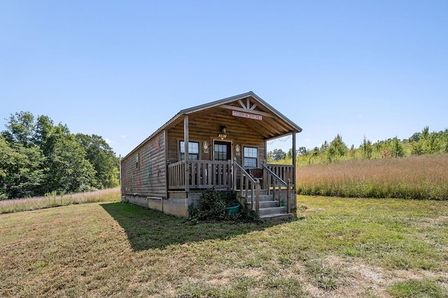 view of front of house with log veneer siding, covered porch, and a front yard