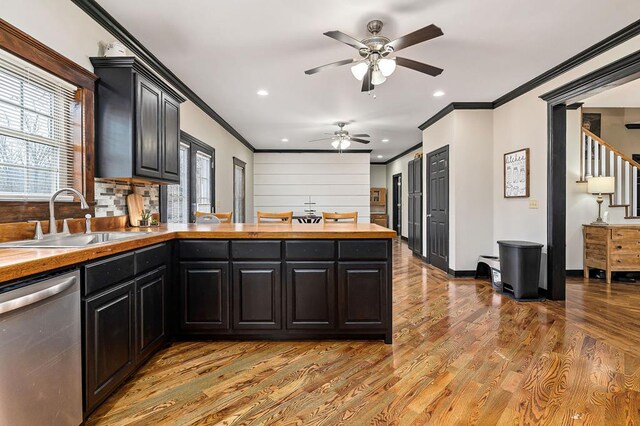 kitchen with crown molding, butcher block counters, a sink, light wood-type flooring, and dishwasher