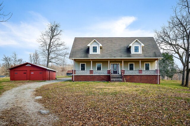 view of front of property featuring a detached garage, dirt driveway, a porch, a front yard, and an outdoor structure