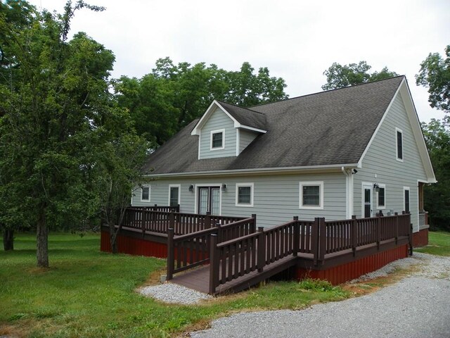 rear view of property featuring a shingled roof, a lawn, and a wooden deck