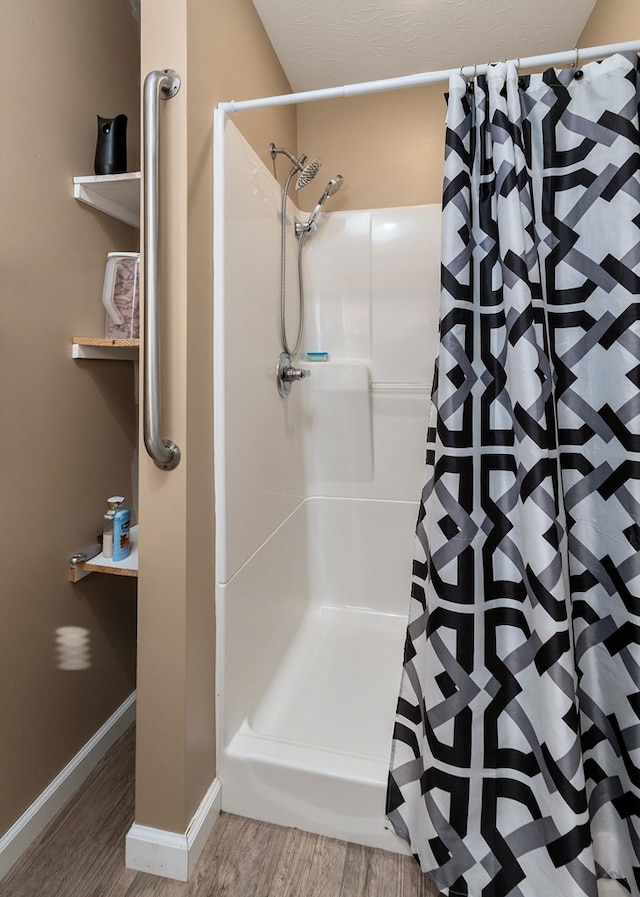 full bathroom with a stall shower, baseboards, and wood finished floors