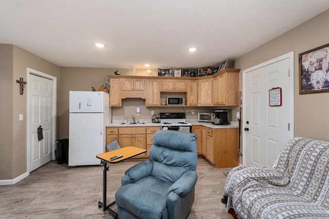 kitchen with light countertops, freestanding refrigerator, a sink, range with electric cooktop, and black microwave