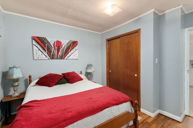 bedroom with a closet, crown molding, baseboards, and wood finished floors