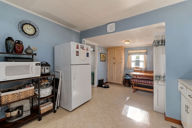 kitchen featuring white appliances, ornamental molding, light countertops, and light floors