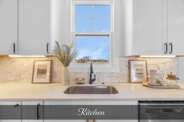 room details with dishwasher, a sink, white cabinetry, and light stone countertops