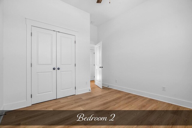 unfurnished bedroom with a ceiling fan, a closet, baseboards, and wood finished floors