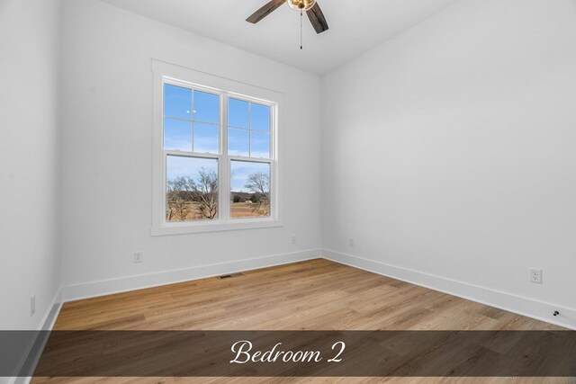 spare room with visible vents, a ceiling fan, light wood-style flooring, and baseboards