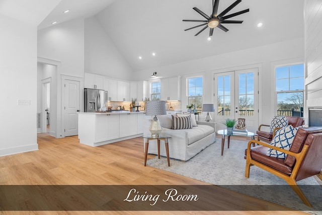 living area with light wood-style floors, high vaulted ceiling, a wealth of natural light, and french doors