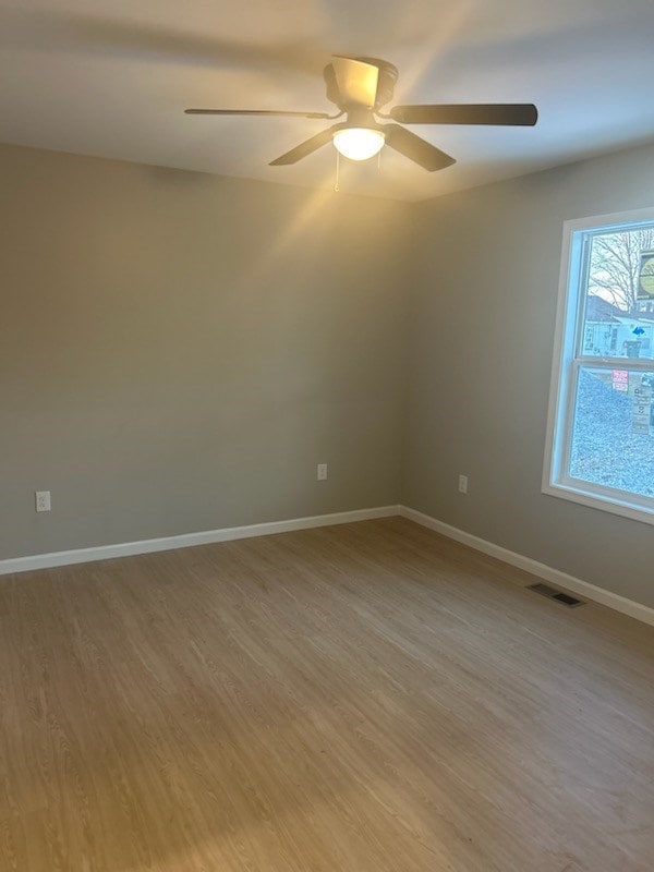 unfurnished room featuring baseboards, visible vents, and wood finished floors