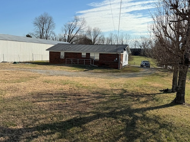 exterior space with an outbuilding, metal roof, brick siding, a yard, and a pole building