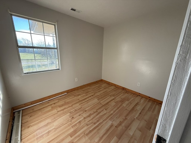 empty room with visible vents, light wood-style flooring, and baseboards